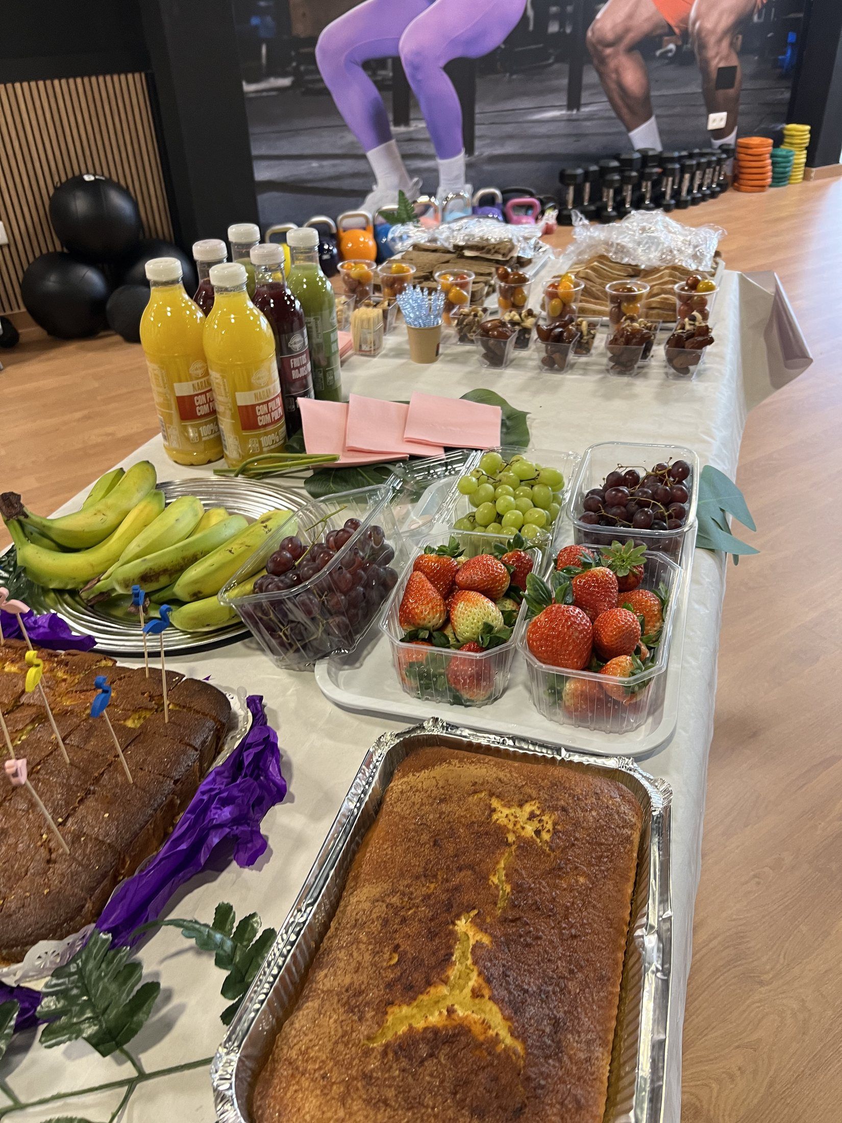 Mesa de desayuno con fruta, bizcochos y zumos en el gimnasio