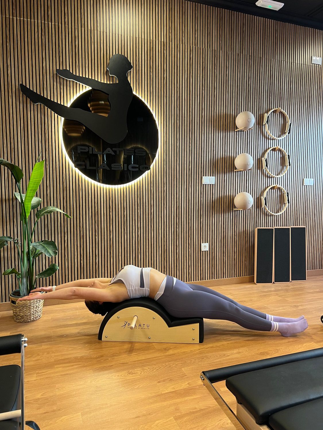Ejercicio sobre el spine corrector frente a la pared de listones con la silueta iluminada